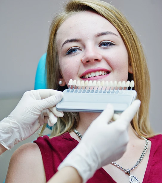 Dentist using a professional tooth shade guide to measure whitening progress for a patient.